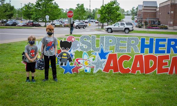 People pose next to superhero sign
